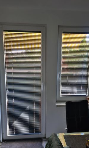 Eleganckie żaluzje aluminiowe 25 mm zamontowane w oknie salonu